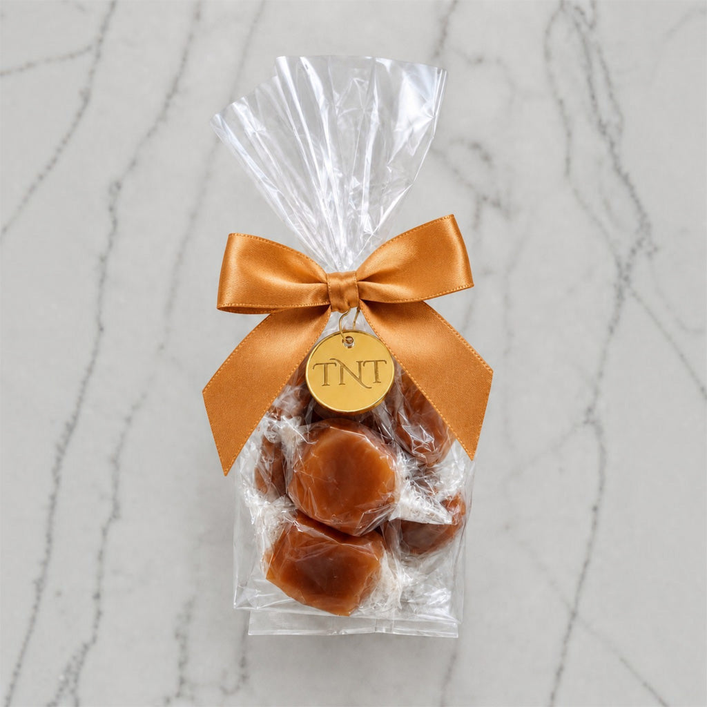 The Accent caramel favor by TNT Sweets with individually wrapped Velvet Heat cayenne caramels, gold satin ribbon, and gold TNT medallion.