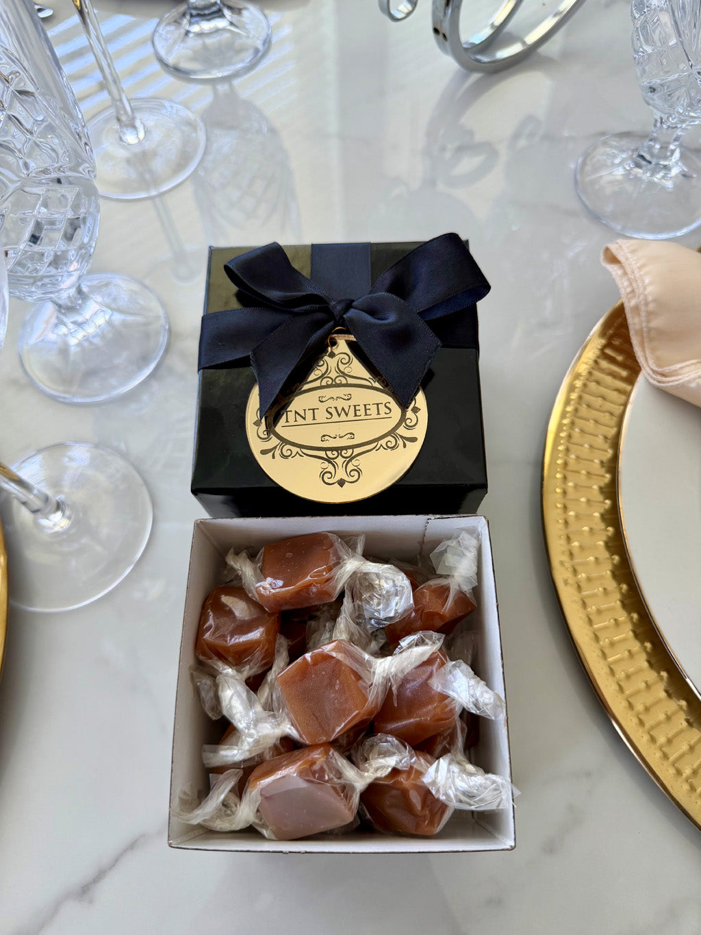 Half-pound of Velvet Heat Cayenne Caramels from TNT Sweets in the black Keepsake Box tied with a black satin ribbon and finished with  a gold acrylic medallion.
