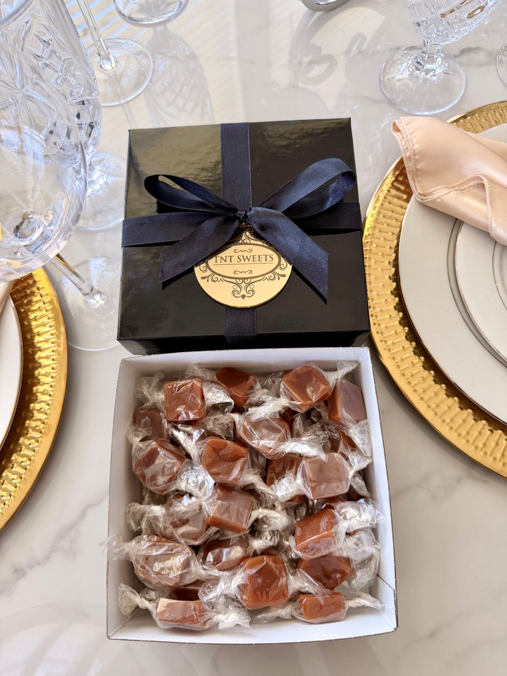 One pound of Velvet Heat Cayenne Caramels from TNT Sweets in the black Keepssake Box tied with a black satin ribbon finished with a gold acrylic medallion.