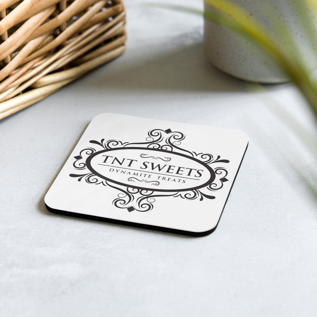 White coaster with black logo on concrete counter with subtle spring decor.