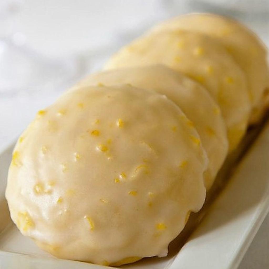 Row of lemon glazed cookies on a white plate with a blurred background.